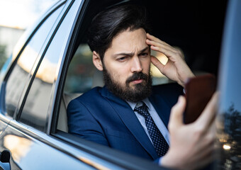 A handsome young businessman is driving in the car