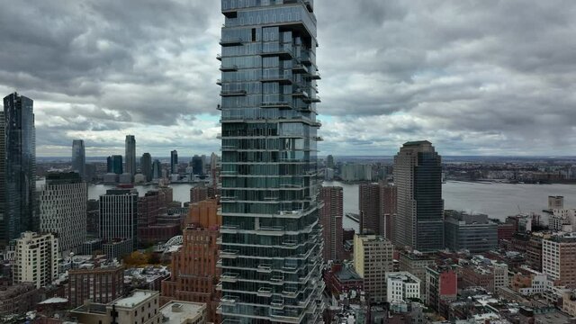 Rising shot of high rise Jenga Tower. Futuristic design building with glass facade and balconies. Cloudy sky. Manhattan, New York City, USA