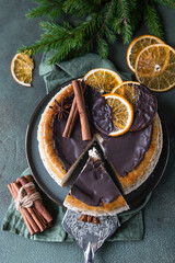 Cheesecake with chocolate decorated slices of dried oranges, cinnamon and anise. Festive Christmas or New Year decoration. Top view.