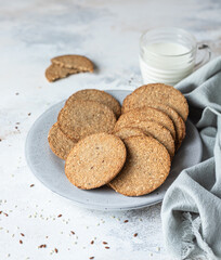 Plate with tasty crackers and a cup of milk. Snack or breakfast on grey stone background.