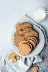 Plate with tasty crackers and a cup of milk. Snack or breakfast on grey stone background.