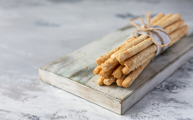 Italian grissini or salted breadsticks on a light stone background. Fresh italian snack with sesame...
