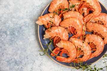 Raw red Argentine shrimps on ceramic plate, blue concrete background. Ocean jumbo shrimps. Top view.
