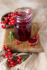 Glass jar with red currant jelly or jam and fresh red currant berries.