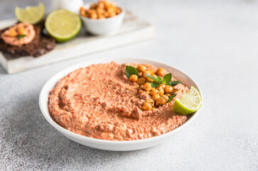 Roasted red pepper hummus garnish with mint and lime. Mashed chickpeas with red bell pepper, lime and mint. Vegetarian snack.