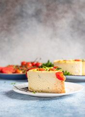 Piece of savoury tomato cheesecake with herbs decorated mint, blue concrete background.