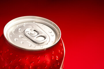 Soft drink in red aluminum bottle with drops at red background. Close up of detail