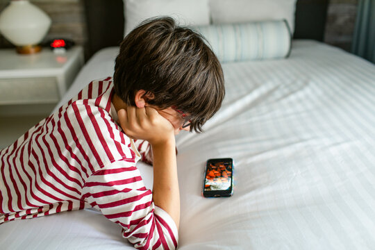 Boy watching smartphone in bedroom