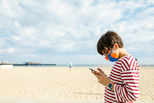 Teen looking phone by the beach