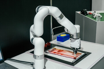 Partially blurred robot with automatic gripping claws and many joints, able to grip and control various objects. Robot holds paintbrush and draws stripes on sheet of paper