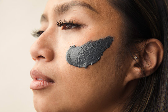 Model wearing grey clay mask on her face