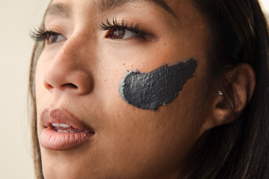 Model wearing grey clay mask on her face
