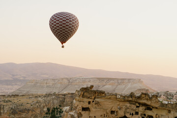 Fototapeta na wymiar Cappadocia, Turkey - 21 July 2021: Colorful hot air balloon flying over white mountains. Hot air balloons flying in sunrise sky. Goreme mountains scenic view