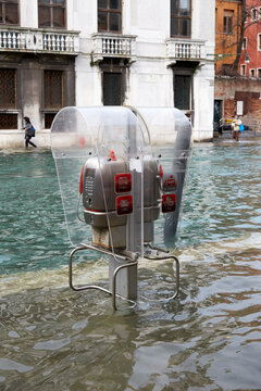 Public call phone telephone box at High tide flood in Venice