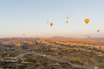 Cappadocia, Turkey - 21 July 2021: Colorful hot air balloon flying over white mountains. Hot air balloons flying in sunrise sky. Goreme mountains scenic view