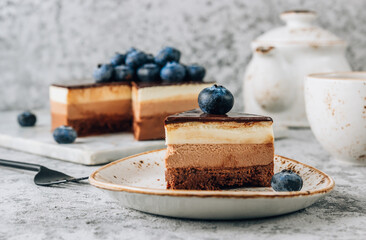 Triple chocolate mousse cake covered with chocolate mirror glaze decorated with fresh berries.