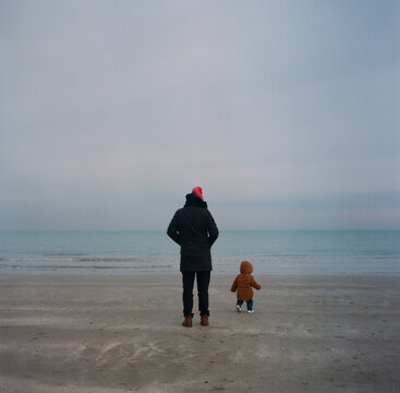 A baby with a father walking by the sea