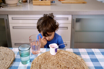 Sleepy child eating yogurt
