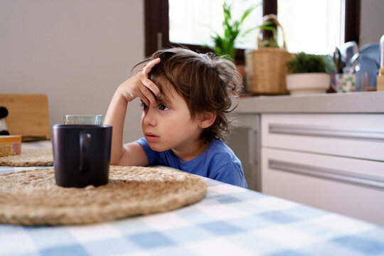 Little kid having breakfast in kitchen