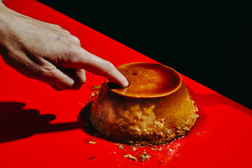 man sticks his forefinger in a creme caramel