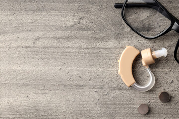 Concept of health care with hearing aid on gray wooden background