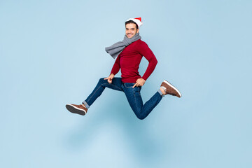 Obraz na płótnie Canvas Young happy handsome Caucasian man in Christmas outfit jumping in isolated color light blue background