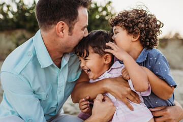 Fototapeta premium Toddler laughing while family kisses him