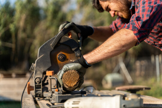 Man sawing a piece of wood outdoors