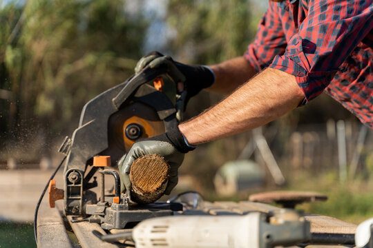 Man sawing a piece of wood outdoors