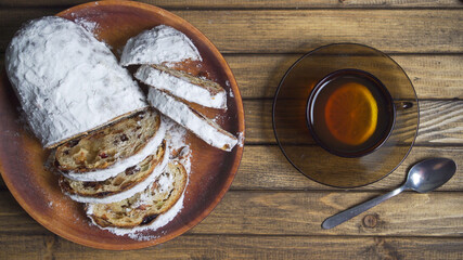 Mug of tea with lemon and spoon on rustic table decoration for delicious dessert. Bake on plate, soft focus.
