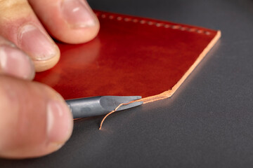 The process of making leather goods. The hands of the master work with a leather product.