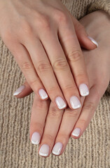 Classic white manicure on natural wool background.
