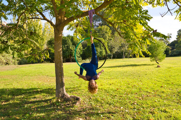 Blonde woman and young gymnast acrobat athlete performing aerial exercise on air ring outdoors in...