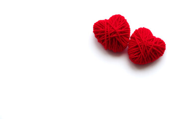 Two red hearts made of yarn on a white background with place for text