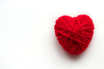One red heart of yarn close-up on a white background with a place for text