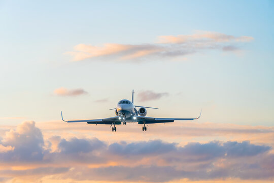 Private jet on the background of a beautiful gentle sky with clouds at sunset in pink and blue tones