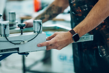 Male worker using a printing machine in a workshop