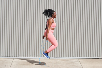 Plus size woman skipping over footpath on sunny day