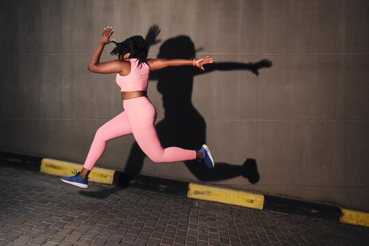 Plus size young woman jumping over road