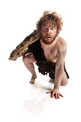 Full-length portrait of dirty man in character of neanderthal climbing with log isolated over white...