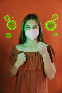 Girl wearing protective face mask standing in fighting stance amidst coronavirus over red background