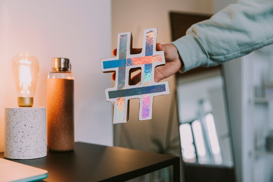 Girl holding holographic hashtag sign at home
