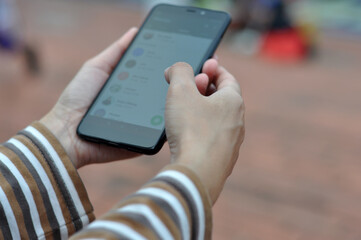 Close-up of a young woman's hand using a mobile phone in a city park