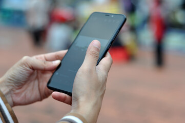 Close-up of a young woman's hand using a mobile phone in a city park