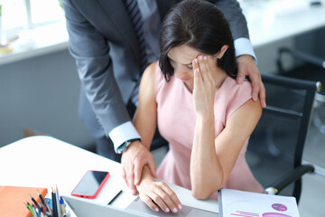 Businessman hugs embarrassed employee in office closeup