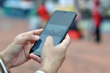 Close-up of a young woman's hand using a mobile phone in a city park