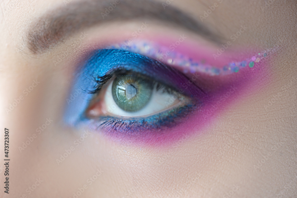 Wall mural Bright blue eye makeup with sparkles closeup