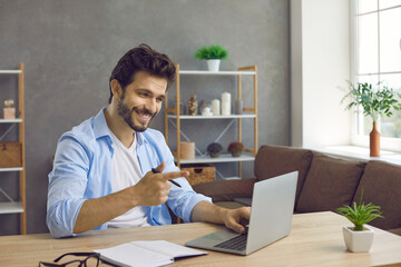 Positive successful man who found what he was looking for points his index finger at laptop as sign of success. Young businessman sitting in office finds idea or good solution for business development