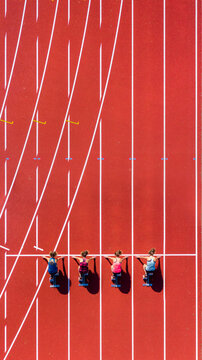 Germany, Baden-Wurttemberg, Winterbach, Aerial view of female sprinters kneeling on starting line