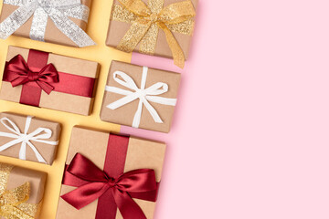 Gifts tied with multicolored ribbons on a pink and golden background. Festive creative layout with copy space.